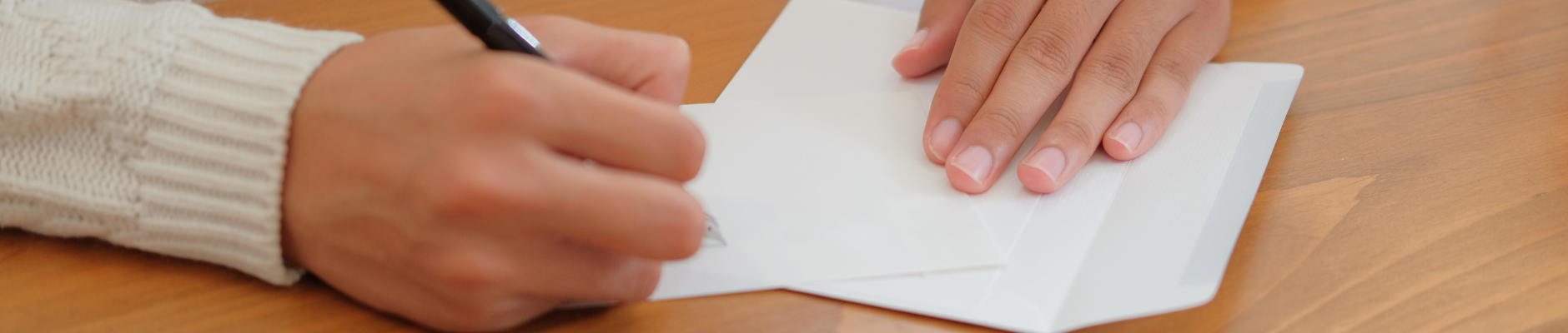 hands writing on a blank greeting card