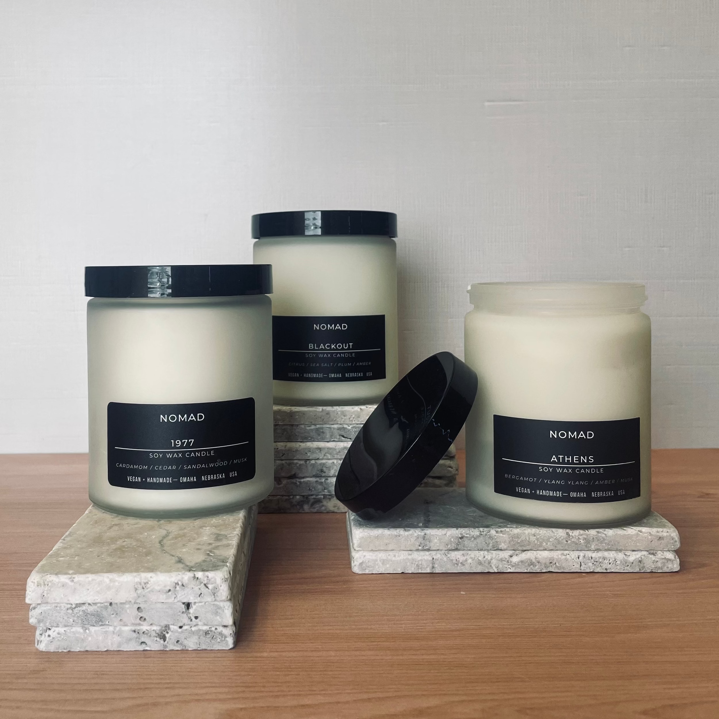 Three candles with black labels on a wooden surface