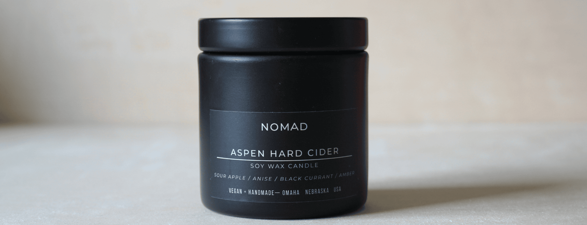 Black candle jar labeled 'Nomad' on a light background