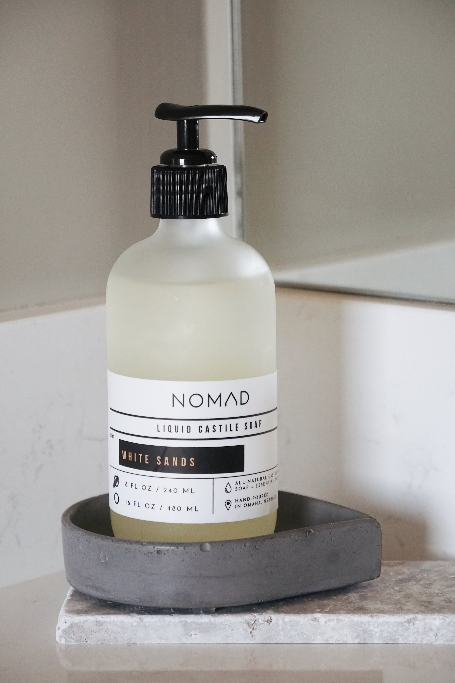 Modern hand soap pump bottle on black drop-shaped concrete soap dish