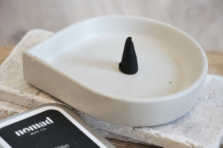 Unlit Incense cone on white drop-shaped concrete incense dish 