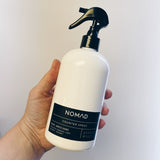 White Nomad counter spray bottle held in hand on white background